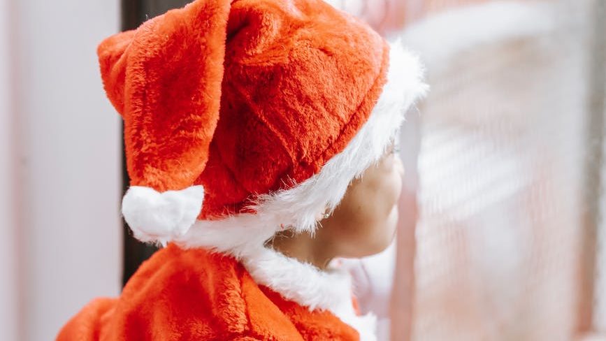 little black boy in santa costume looking in window